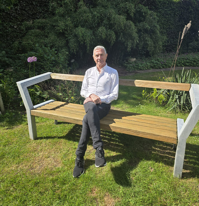 nanowhite_tandenbleken Man in wit overhemd zittend op een parkbank